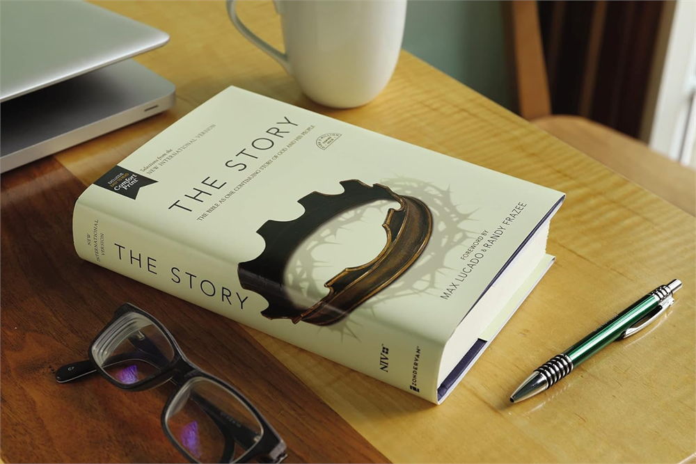 The Story, NIV on a table beside a cup, reading glasses, and a pen.