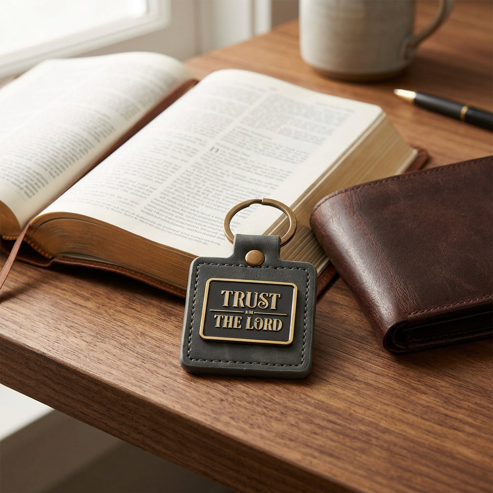 Trust in the Lord gray faux leather keychain resting on an open Bible on a wooden table