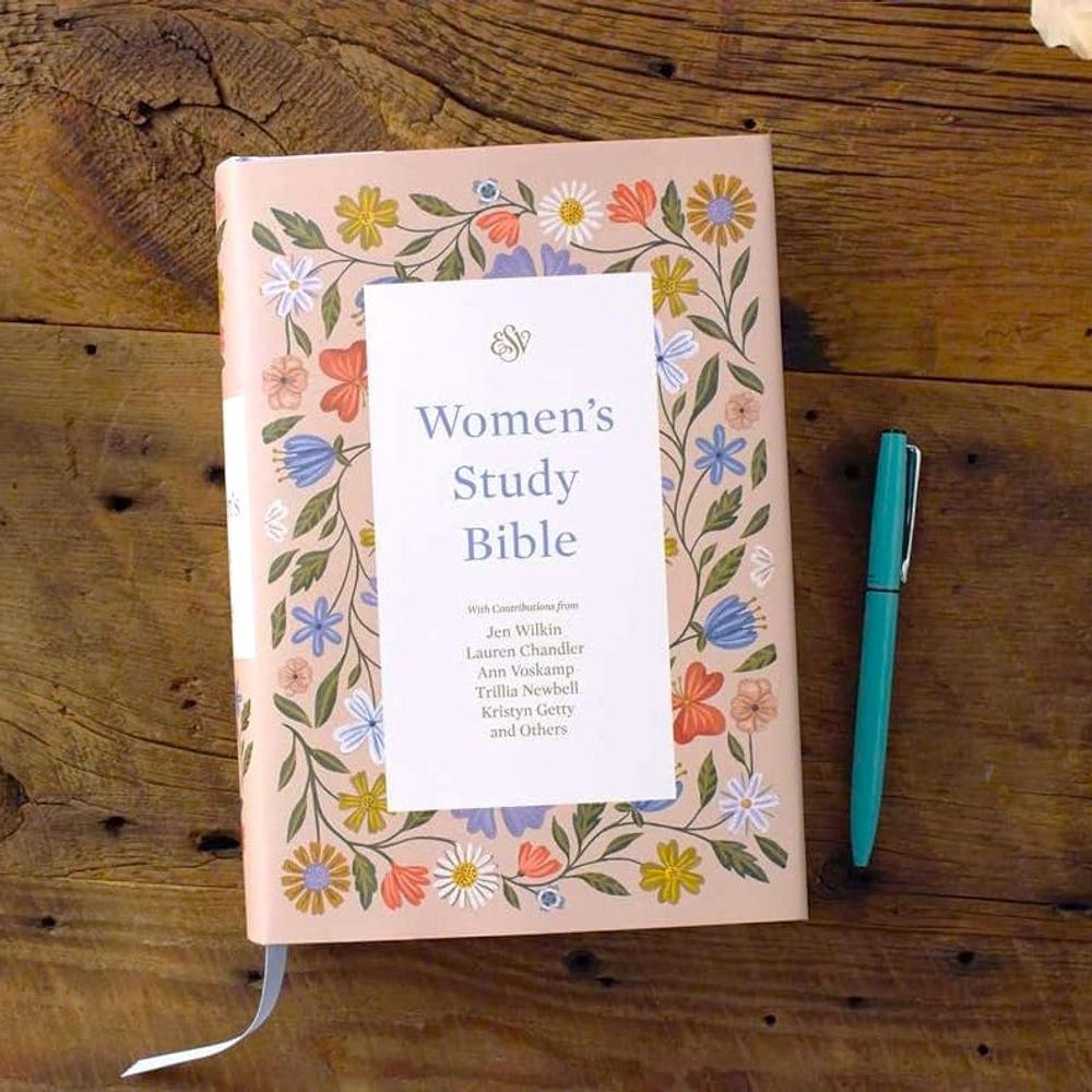 Floral ESV Women's Study Bible resting on a wooden table beside a teal pen.