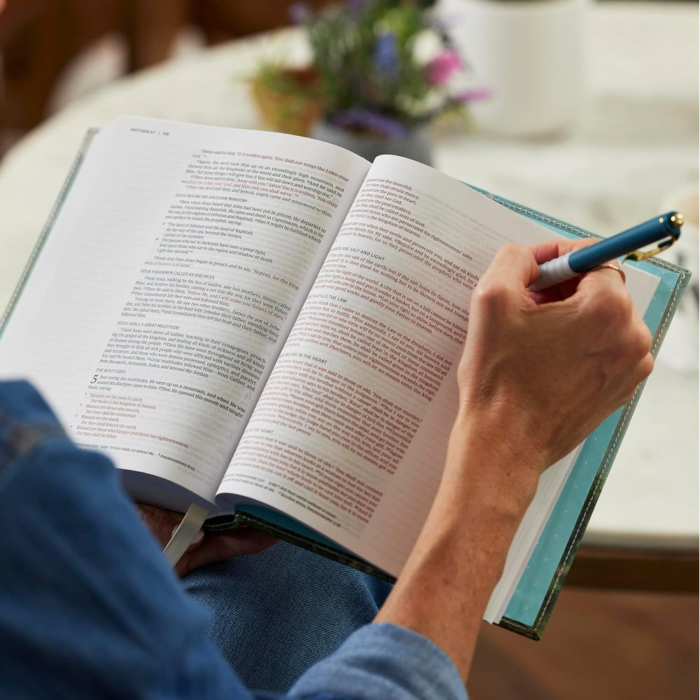 Close view of a reader writing in the wide lined margins of the NKJV Journal the Word Bible.
