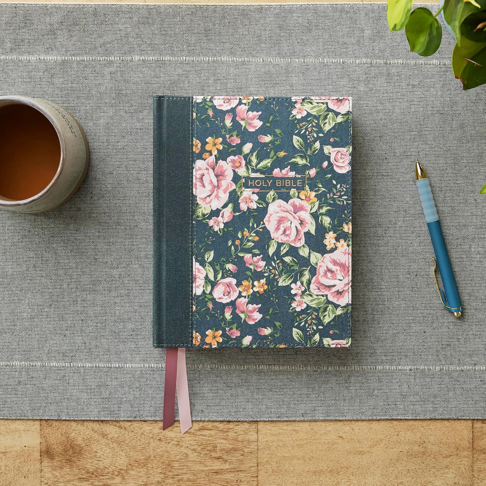 Gray floral NKJV Journal the Word Bible resting closed on a table beside a pen and cup.