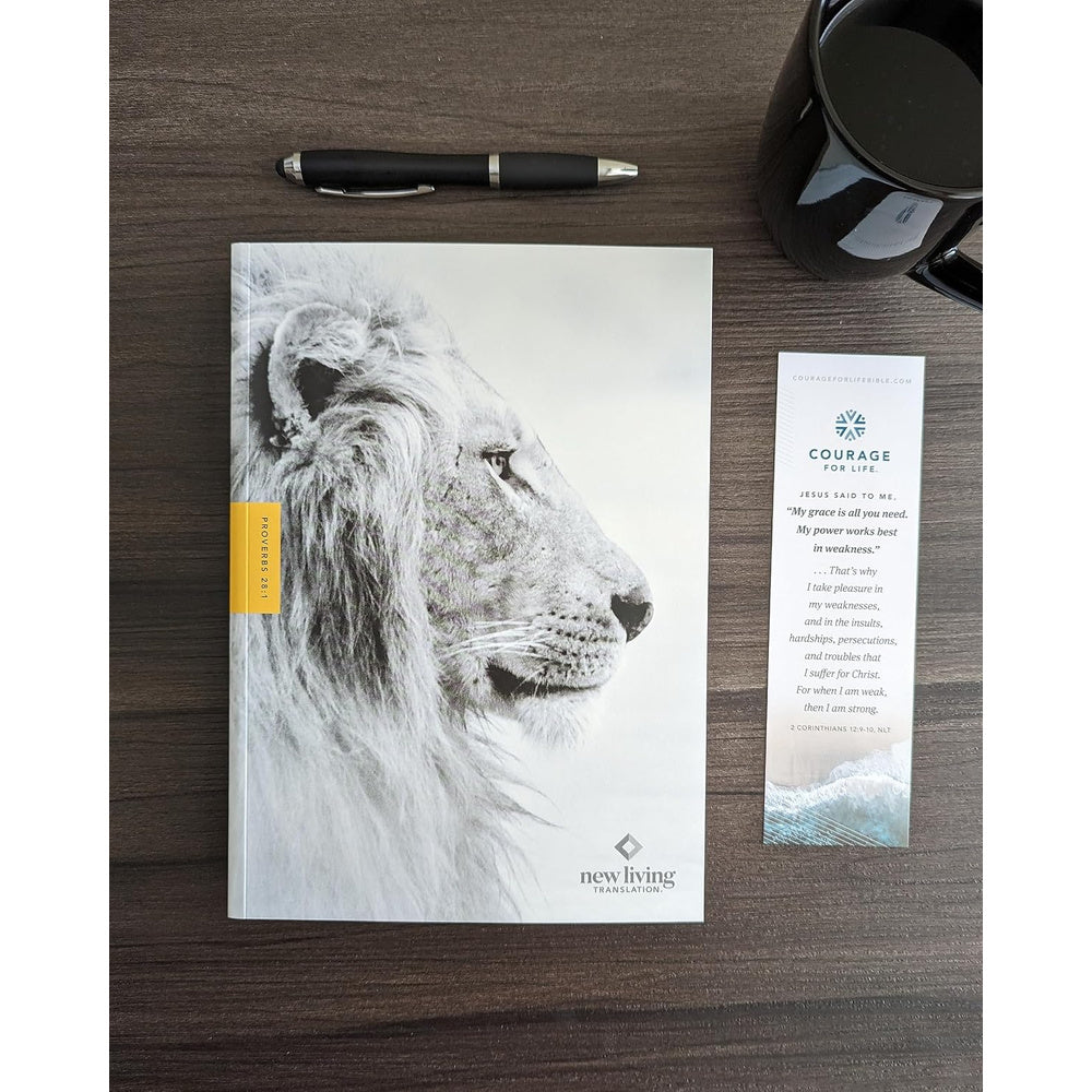 Lion-cover NLT Courage for Life Study Bible for Men resting on a table beside a pen and bookmark.
